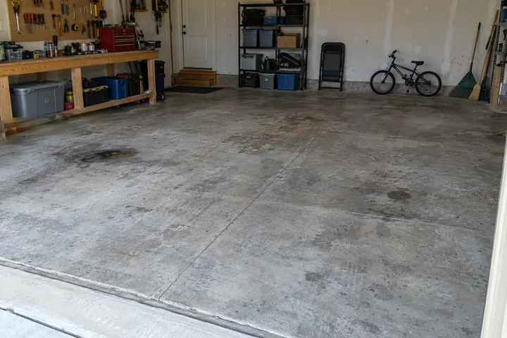 A stained, cracked bare garage floor (example photo)